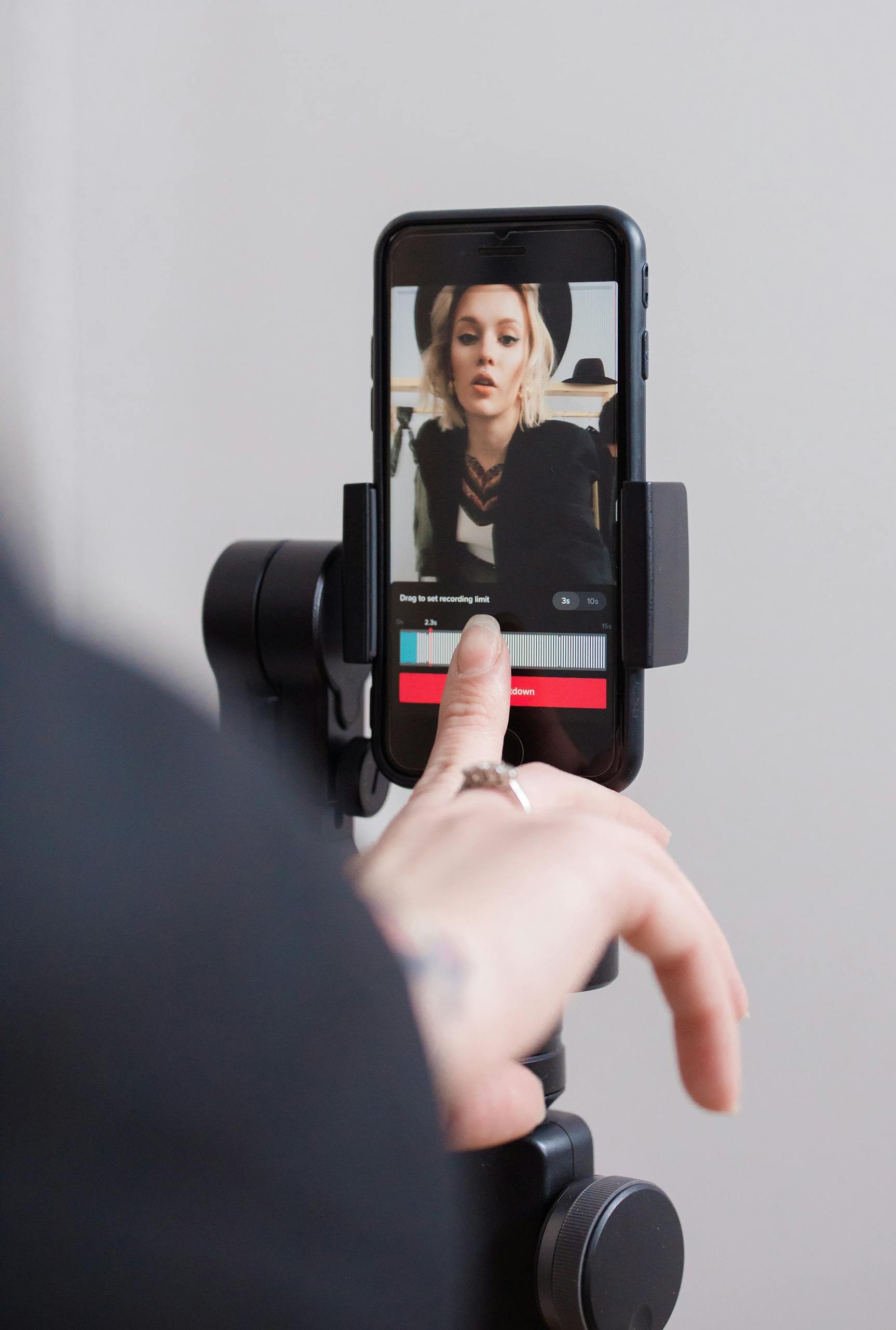 A woman recording a vertical video on her smartphone, focusing on engaging digital content creation.