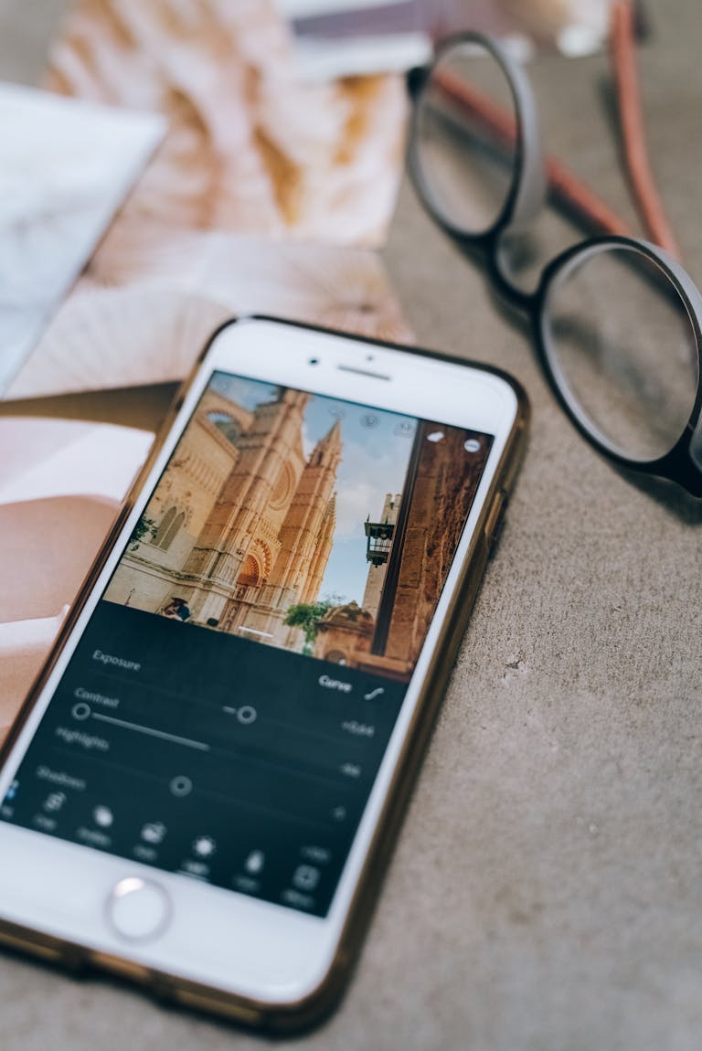 Close-up of smartphone editing a photo with eyeglasses on table.
